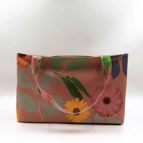 Large teacher/book bag with bright floral daisy design on a dark peach background.