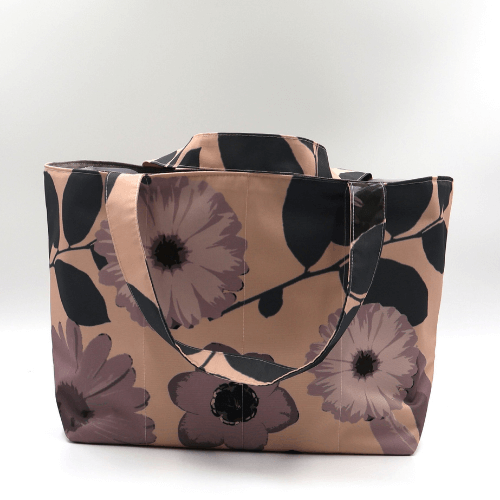 Medium teacher/book bag with daisy floral design in dark and light mauve on a dusky peach background.