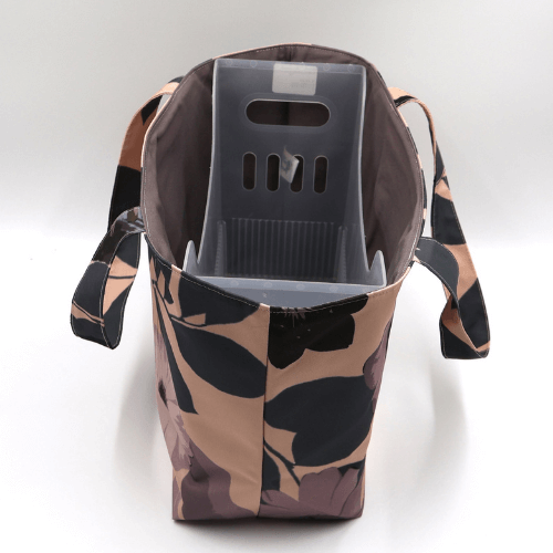 Medium teacher/book bag with daisy floral design in dark and light mauve on a dusky peach background. With plastic inner.