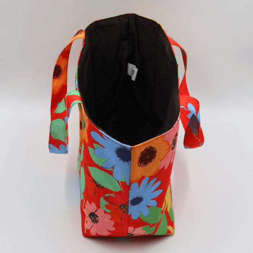 Medium teacher/book bag with bright daisy floral design on a red background. Without plastic inner.