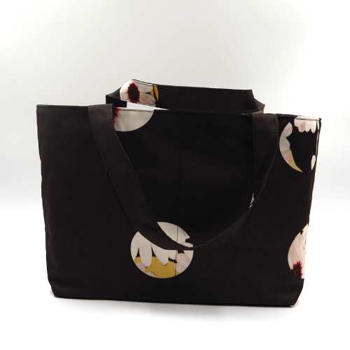 Medium teacher/book bag with white abstract daisy design on a black background. Carry books and crafts.