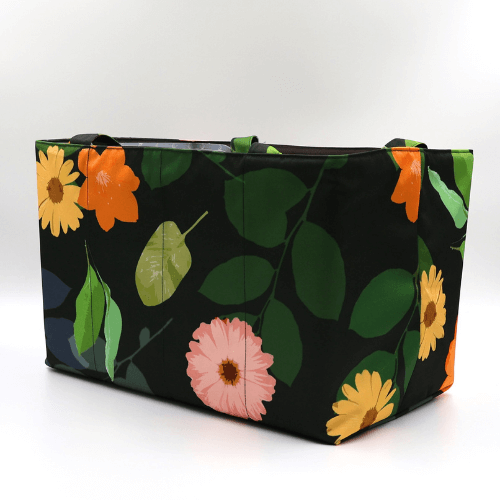 Large teacher/book bag with bright, daisy design on a black background. Carry books and crafts. Side view.