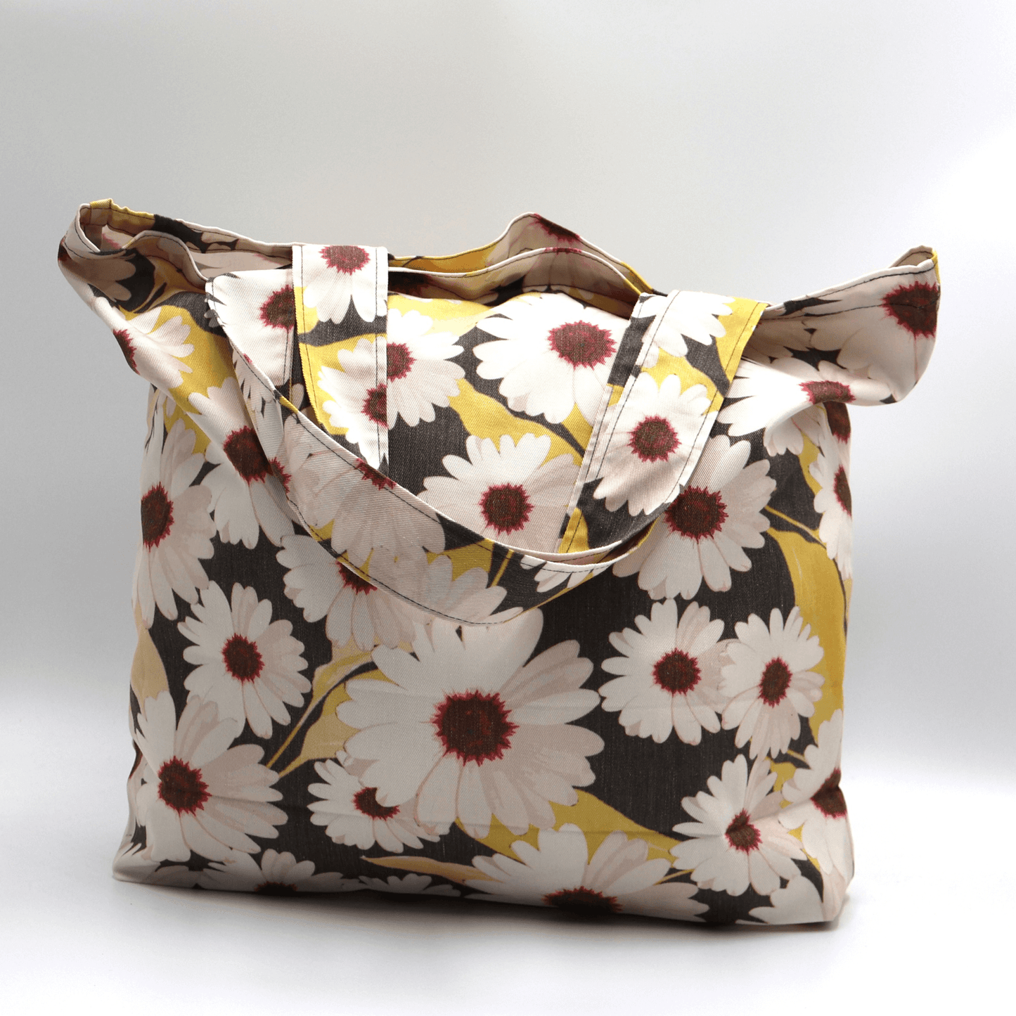 A big, durable tote bag with a white Daisy design. Carry all your daily essentials, books or shopping.