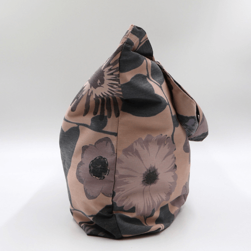 A big, durable tote bag with a mauve and grey daisy design on soft peach background. High-quality materials. Side view.
