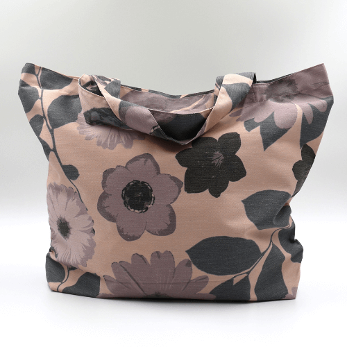 A big, durable tote bag with a mauve and grey daisy design on soft peach background. High-quality materials.