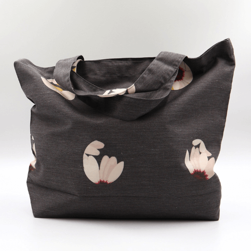 A big, durable tote bag with a white abstract daisy design on black background. High-quality materials.