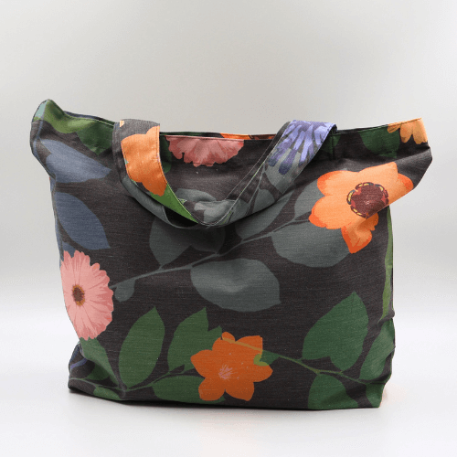 A big, durable tote bag with a bright orange and yellow daisy design on dark grey background. High-quality materials.