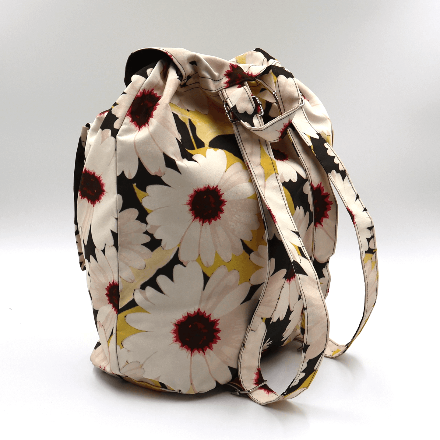 Lightweight backpack with drawstring and white daisy floral design on black background. Back view.