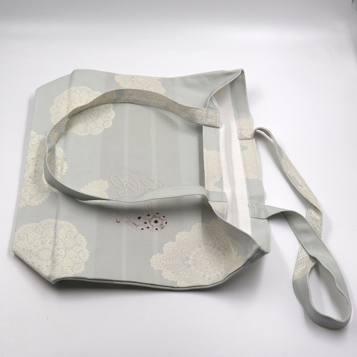 Close up view of a flat laid beige cotton canvas shopper tote bag displaying the high quality neat stitching details along the handle seams