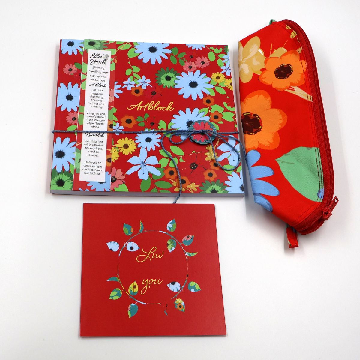 Individual stationery items shown separately flat lay style including a thick white paper artist sketchpad a durable lined polyester canvas pencil pouch and an illustrated greeting card
