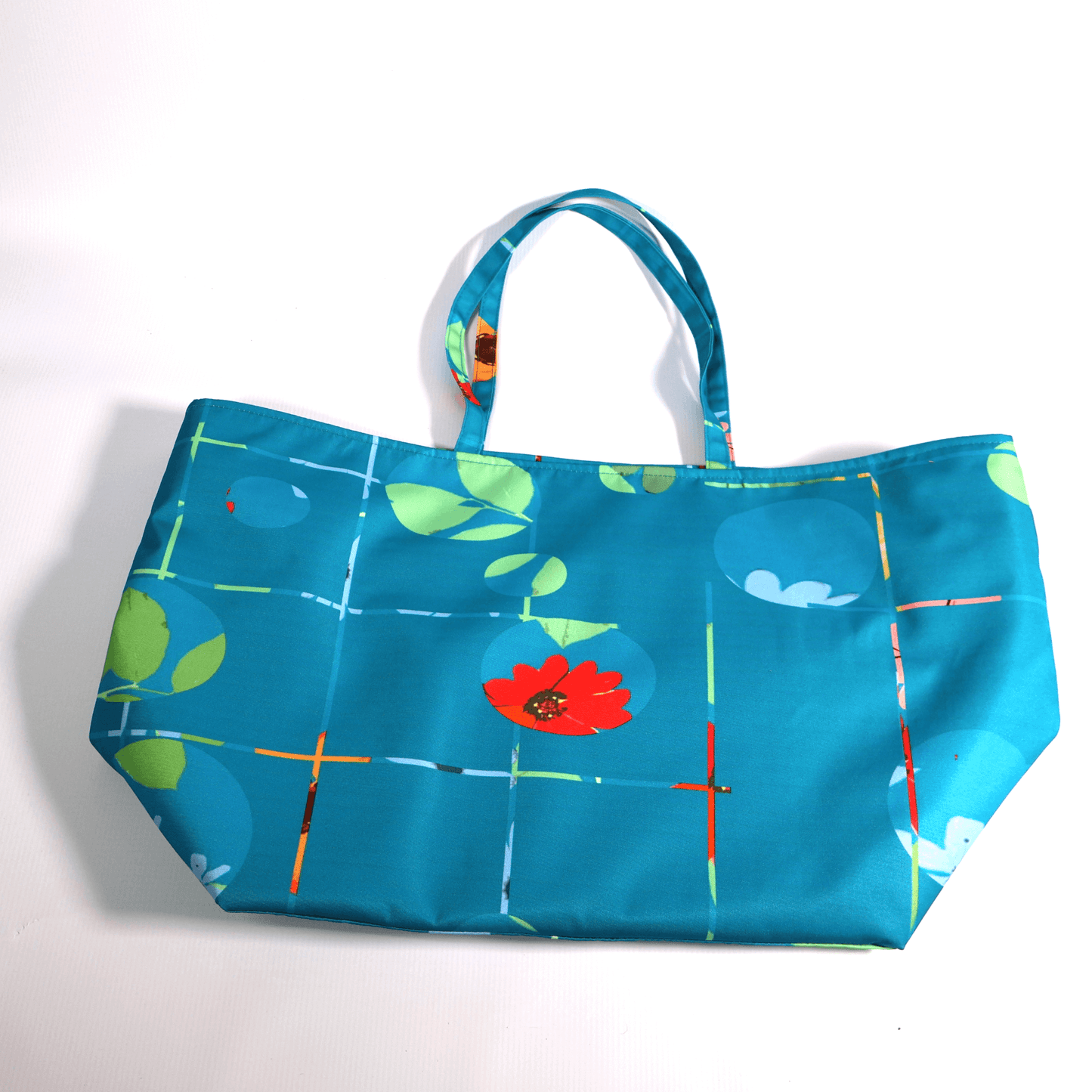 A bright turquoise/blue carryall bag with a multi-colour daisy design. Flat view.