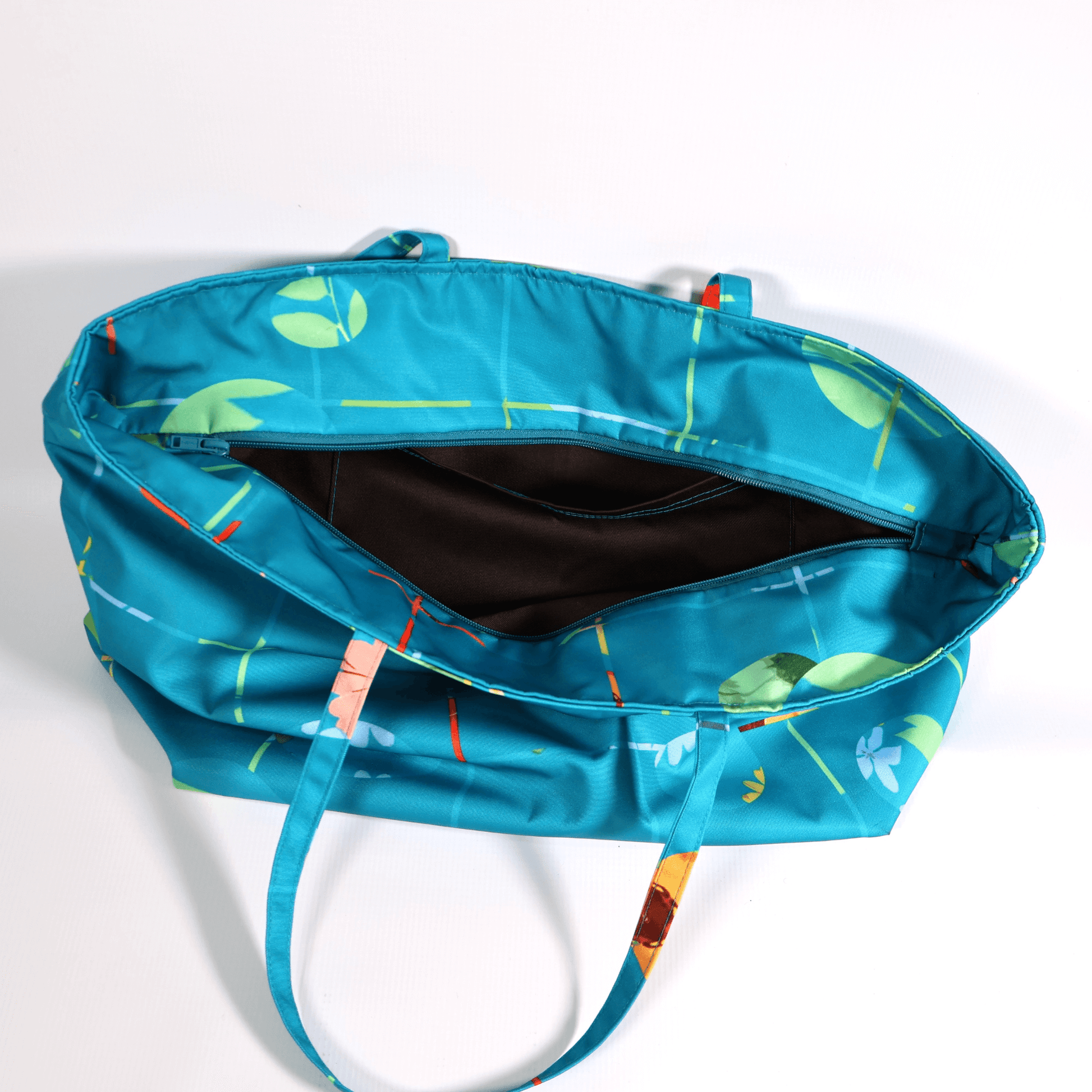 A bright turquoise/blue carryall bag with a multi-colour daisy design. Top view.