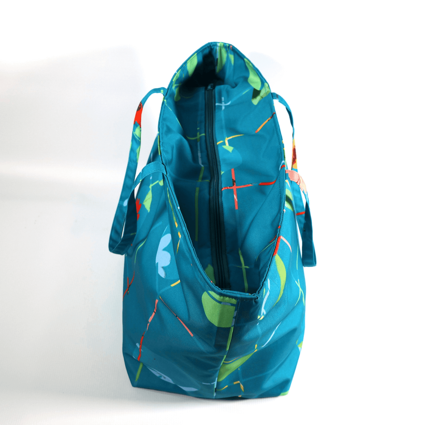 A bright turquoise/blue carryall bag with a multi-colour daisy design. Open zipper.