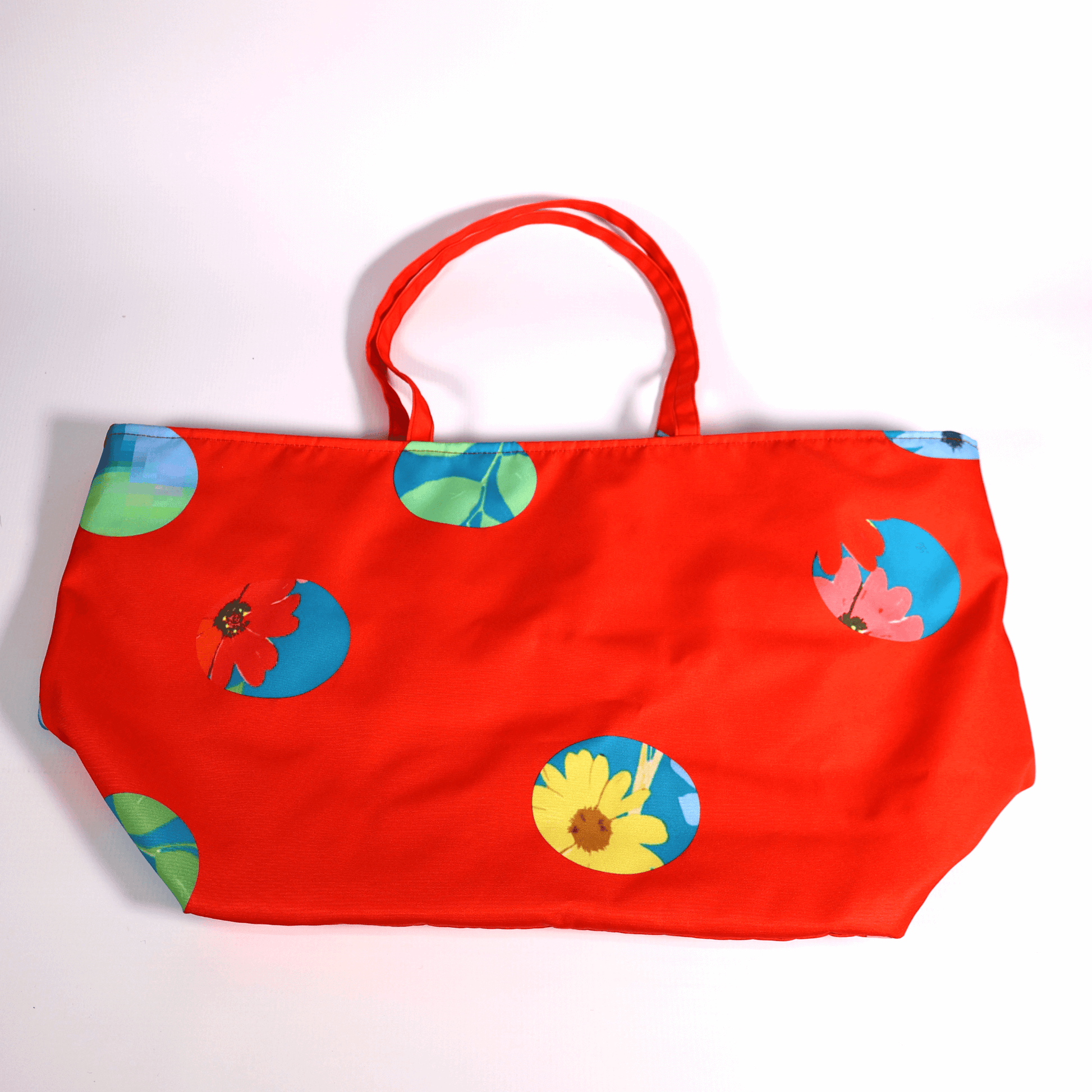 A bright red carryall bag with a stripe abstract floral design. Flat view.
