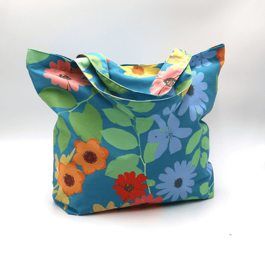 A bright, beautiful tote bag with Daisy design on a blue background. Perfect finishes. Side angle.