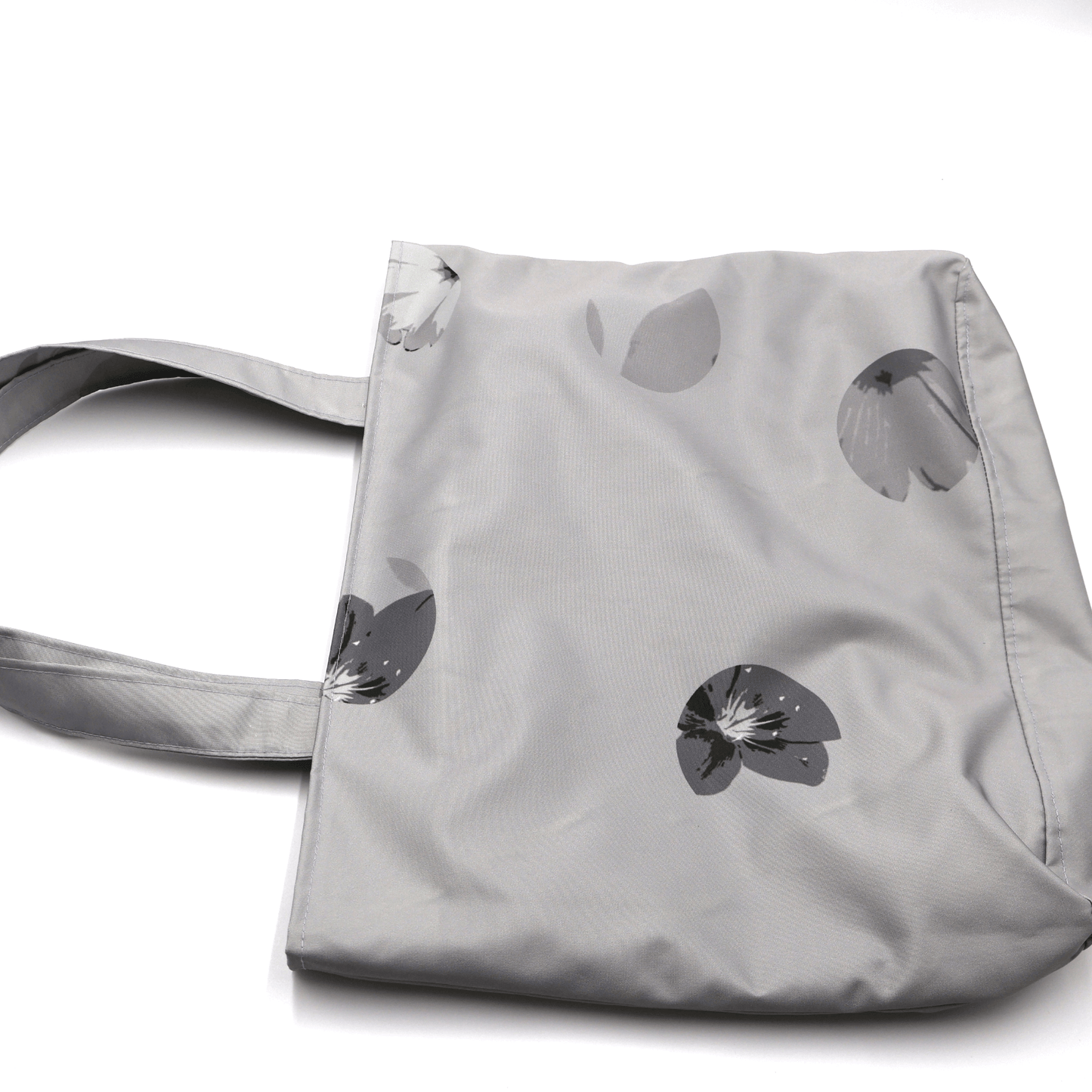 Shoulder bag with daisy floral design in dark and light grey. Perfect for carrying books and documents. Flat view.