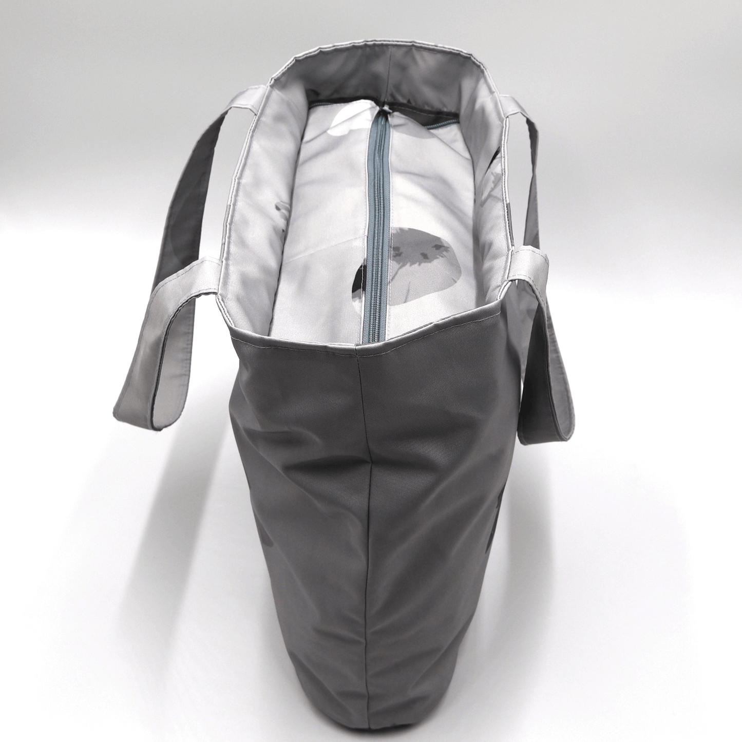 Shoulder bag with daisy floral design in dark and light grey. Zipped closure. Top view.