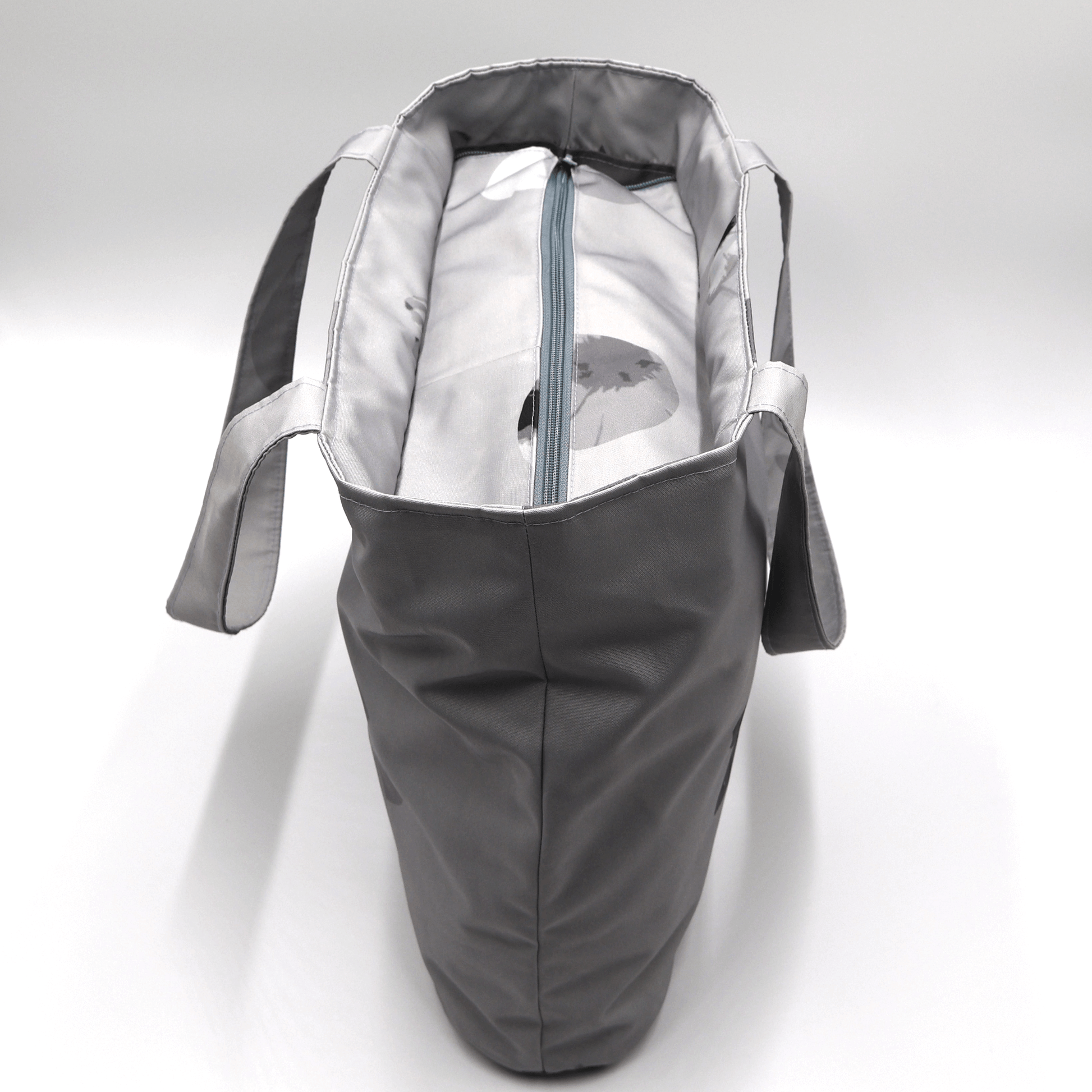 Shoulder bag with daisy floral design in dark and light grey. Zipped closure. Top view.