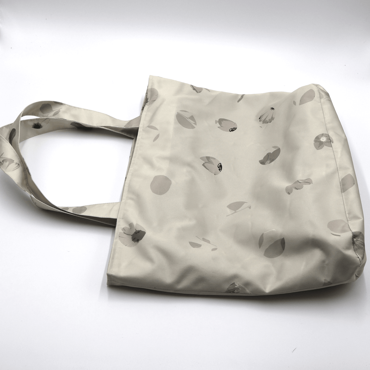 Shoulder bag with daisy floral design in beige, ivory and taupe. Perfect for carrying books and documents. Flat view.