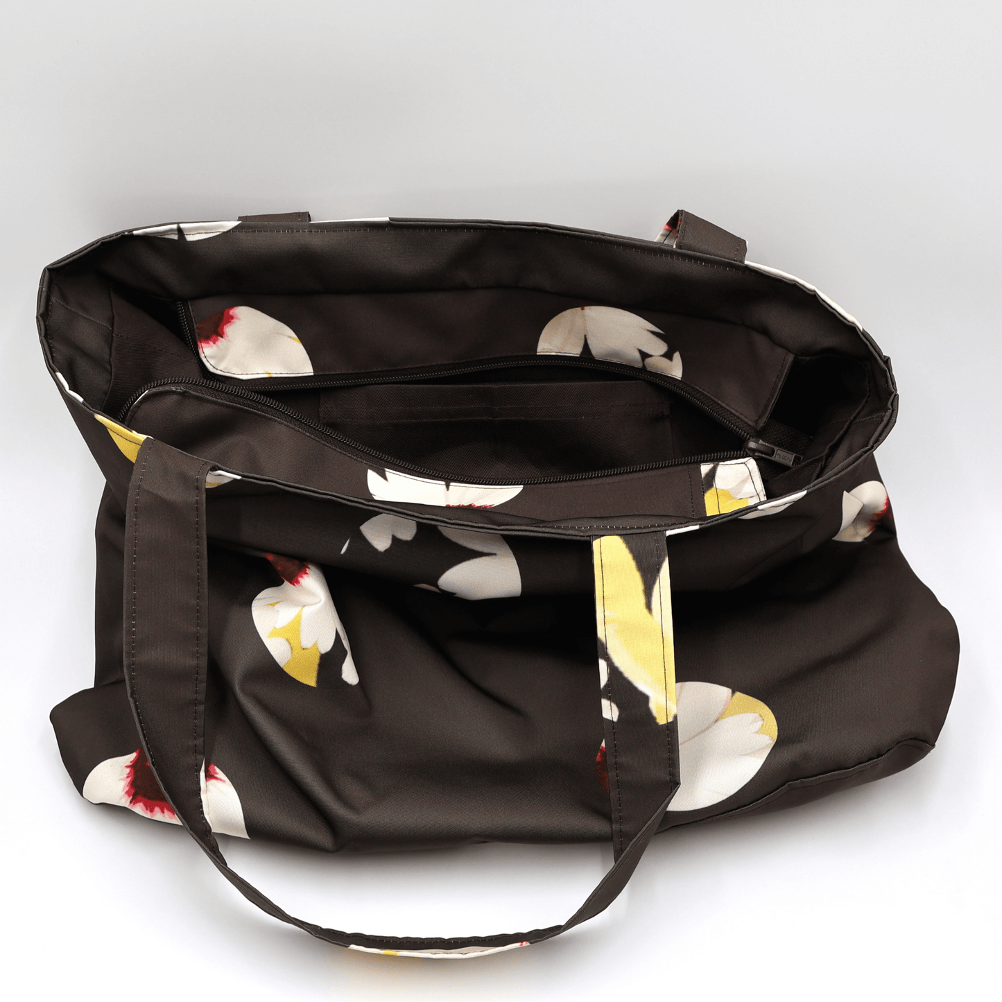Shoulder bag with white abstract daisy design on a black background. Perfect for carrying books and documents. Inside view.