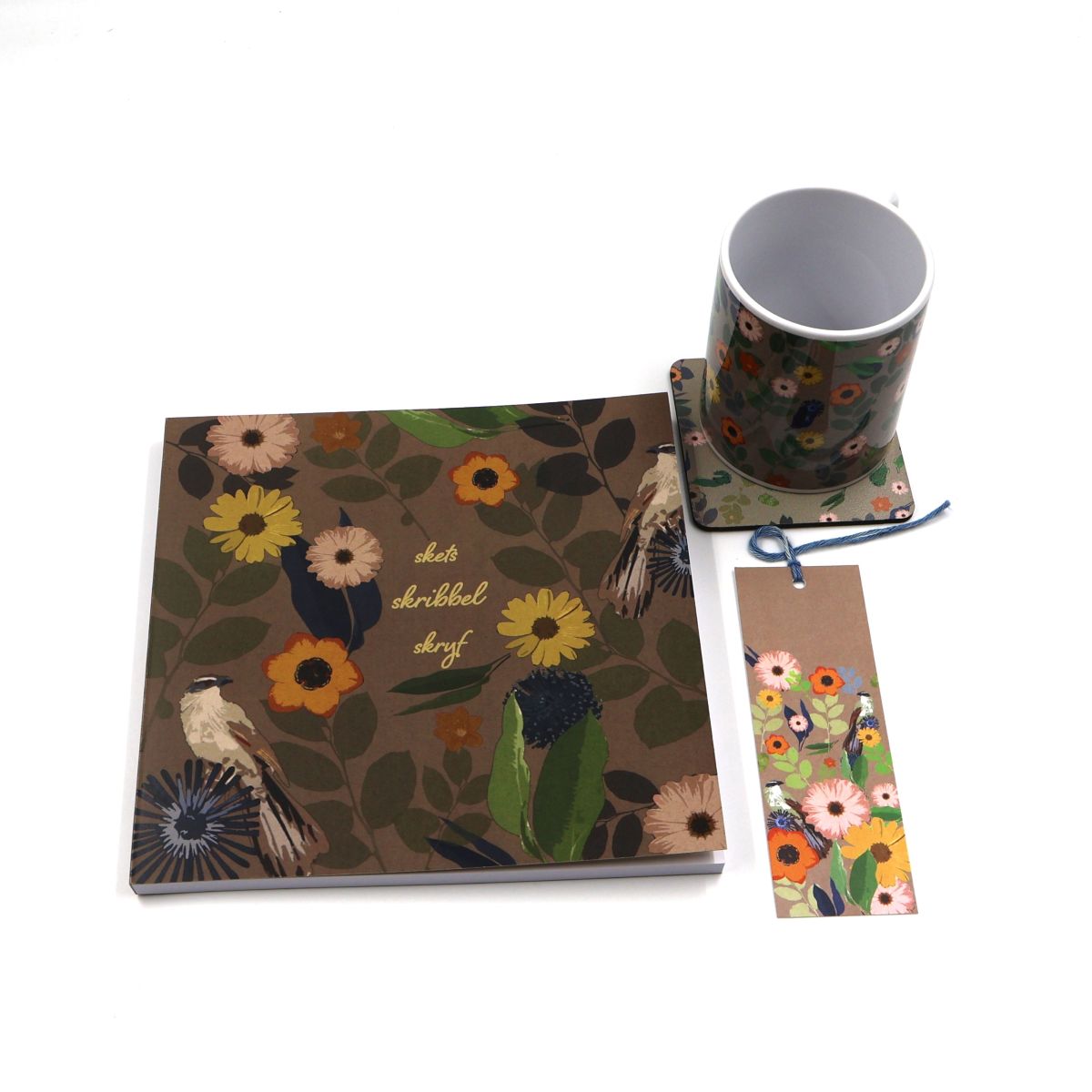 Individual botanical stationery and lifestyle items shown separately flat lay style including a thick paper square twenty by twenty centimeter sketchpad a patterned mug coaster and bookmark