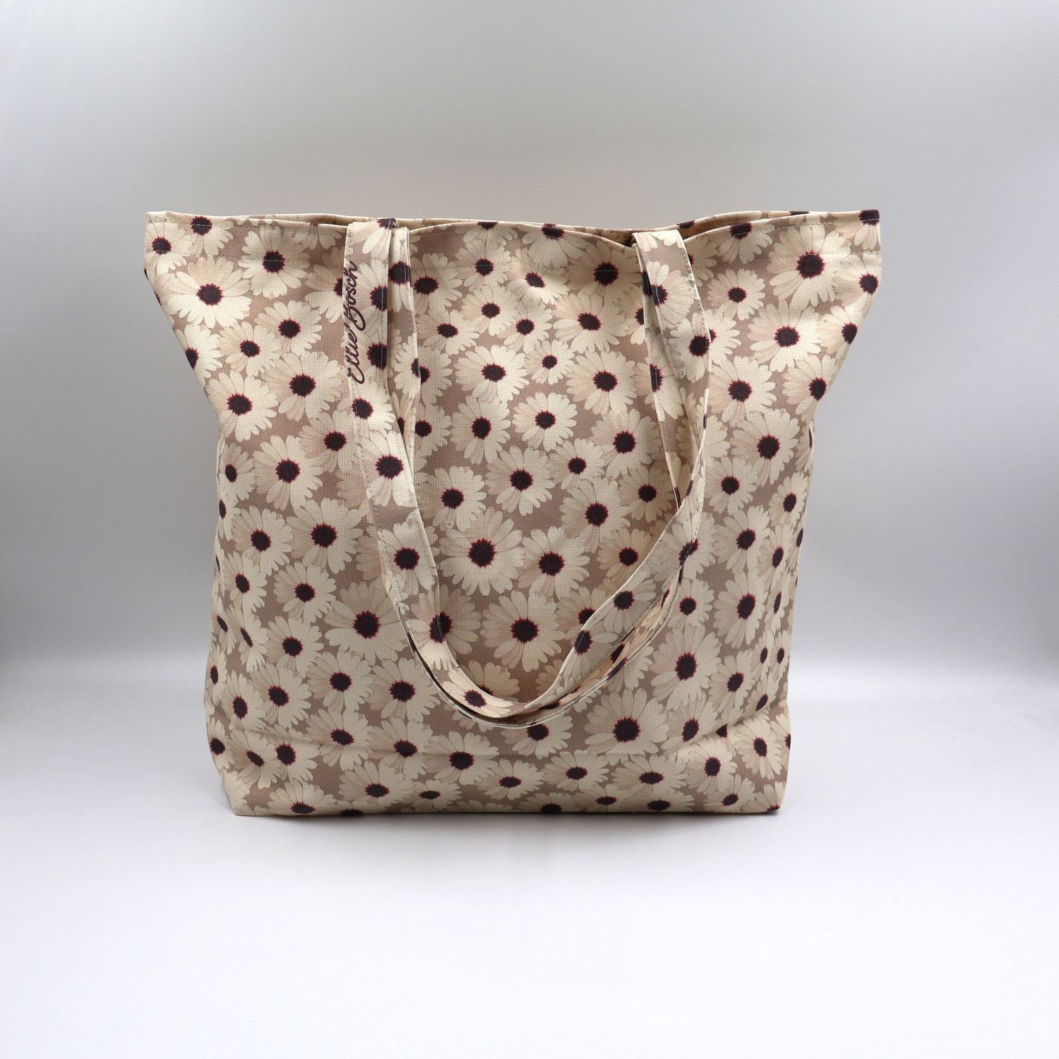 Close-up detail of the cheerful small white daisy print on the fabric of the ladies mushroom beige canvas tote bag, highlighting the premium fabric texture.