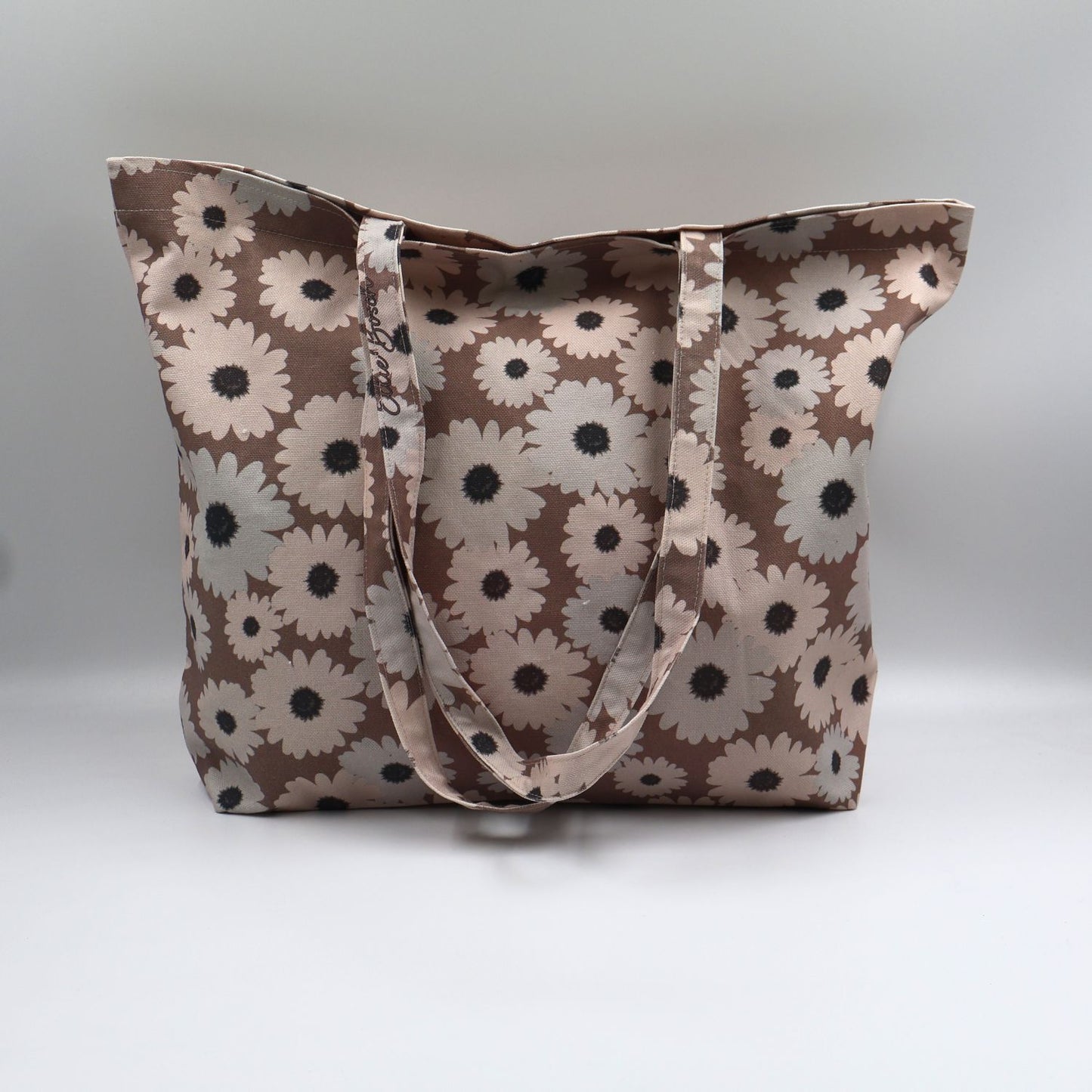 Close-up detail of the grey and beige wildflower print on the front panel of the ladies sandstone brown canvas tote bag, highlighting the premium fabric texture.