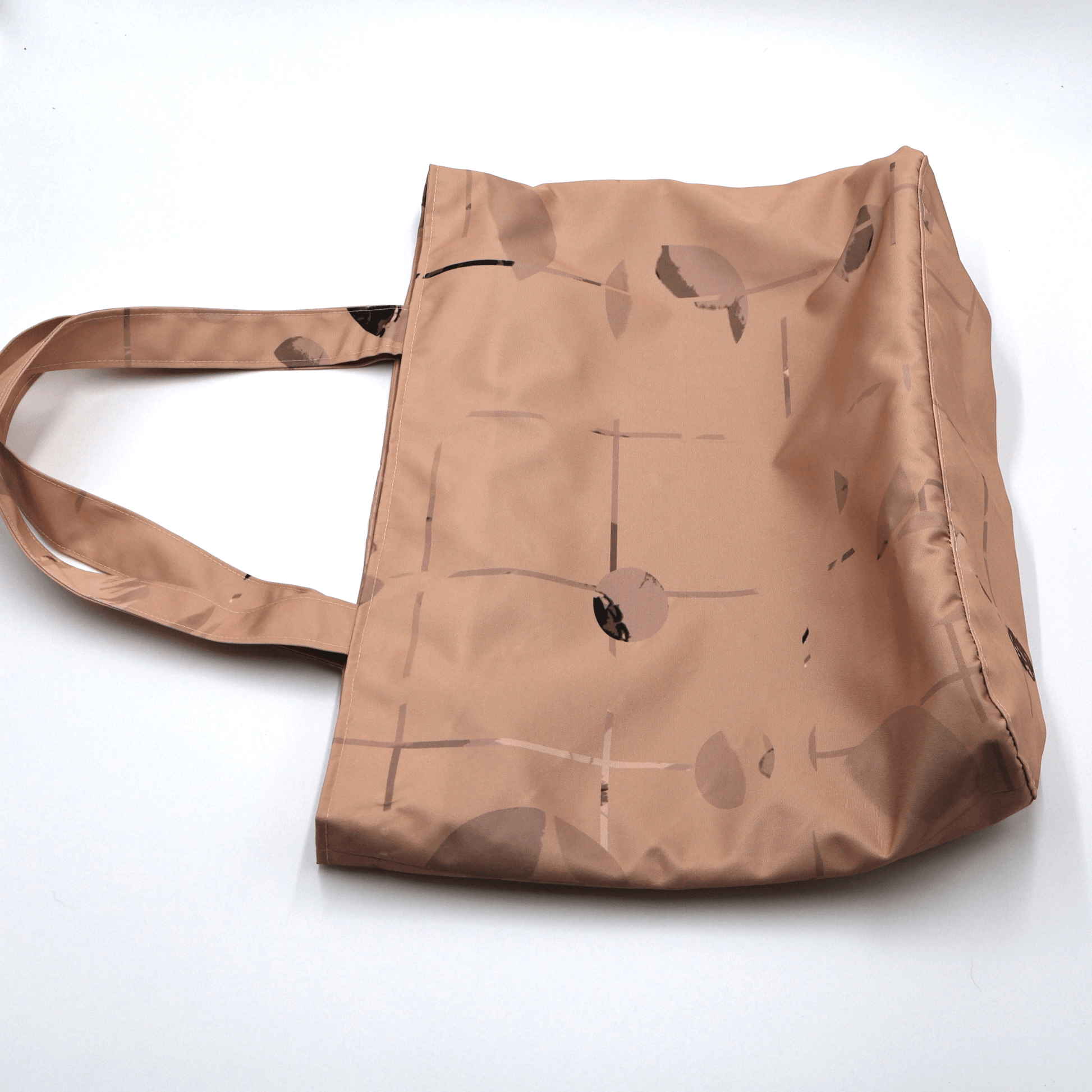 Close-up of the Ellie B Peach Moon print on a canvas tote bag, showcasing the rusty orange and warm brown wind-blown petals surface design.