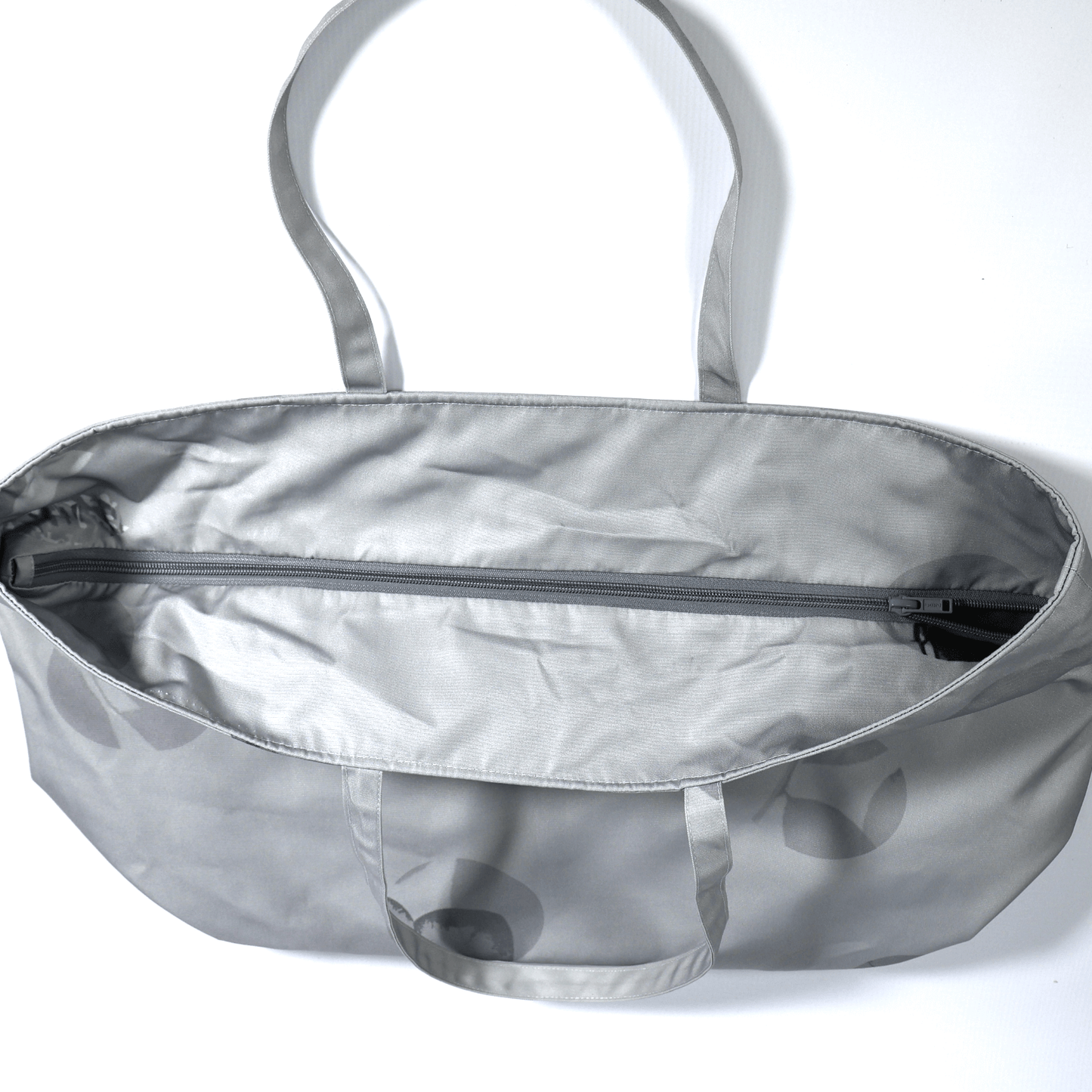 Secure top zip closure on a spacious light grey canvas travel tote bag showing internal storage capacity for daily essentials. 