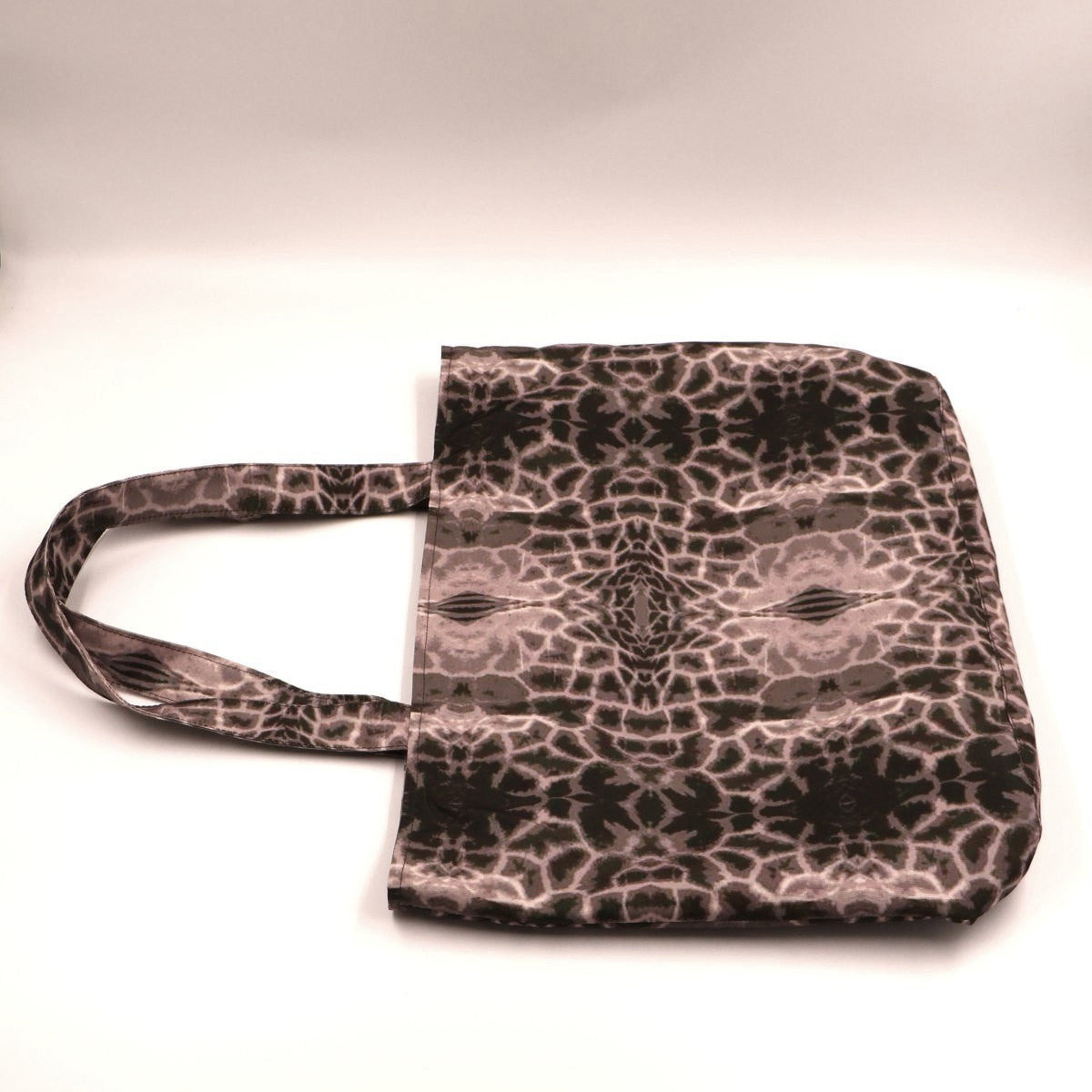 Flat lay view of Letheba muted grey giraffe spot shopper bag showing secure top zipper closure