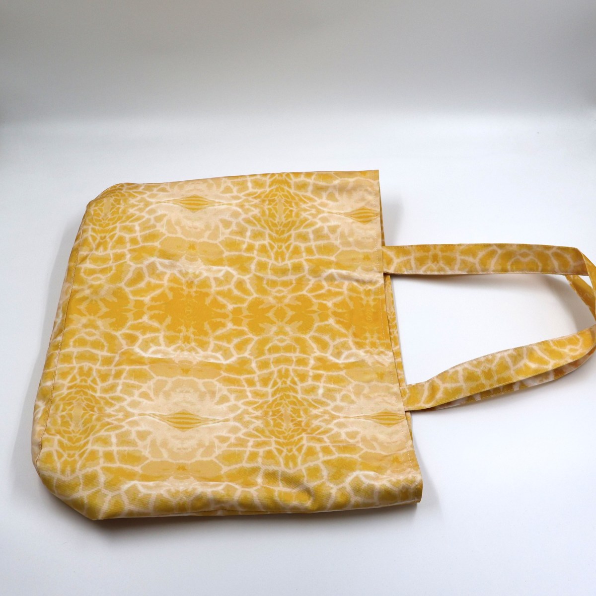 Flat lay view of Letheba radiant bold yellow giraffe spot book bag showing secure top zipper