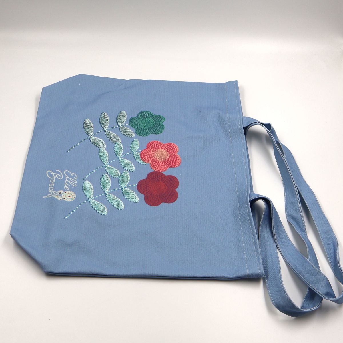 Flat lay view of a wide forty six centimeter by forty two centimeter blue cotton canvas shopper tote displaying the full decorative floral pattern layout