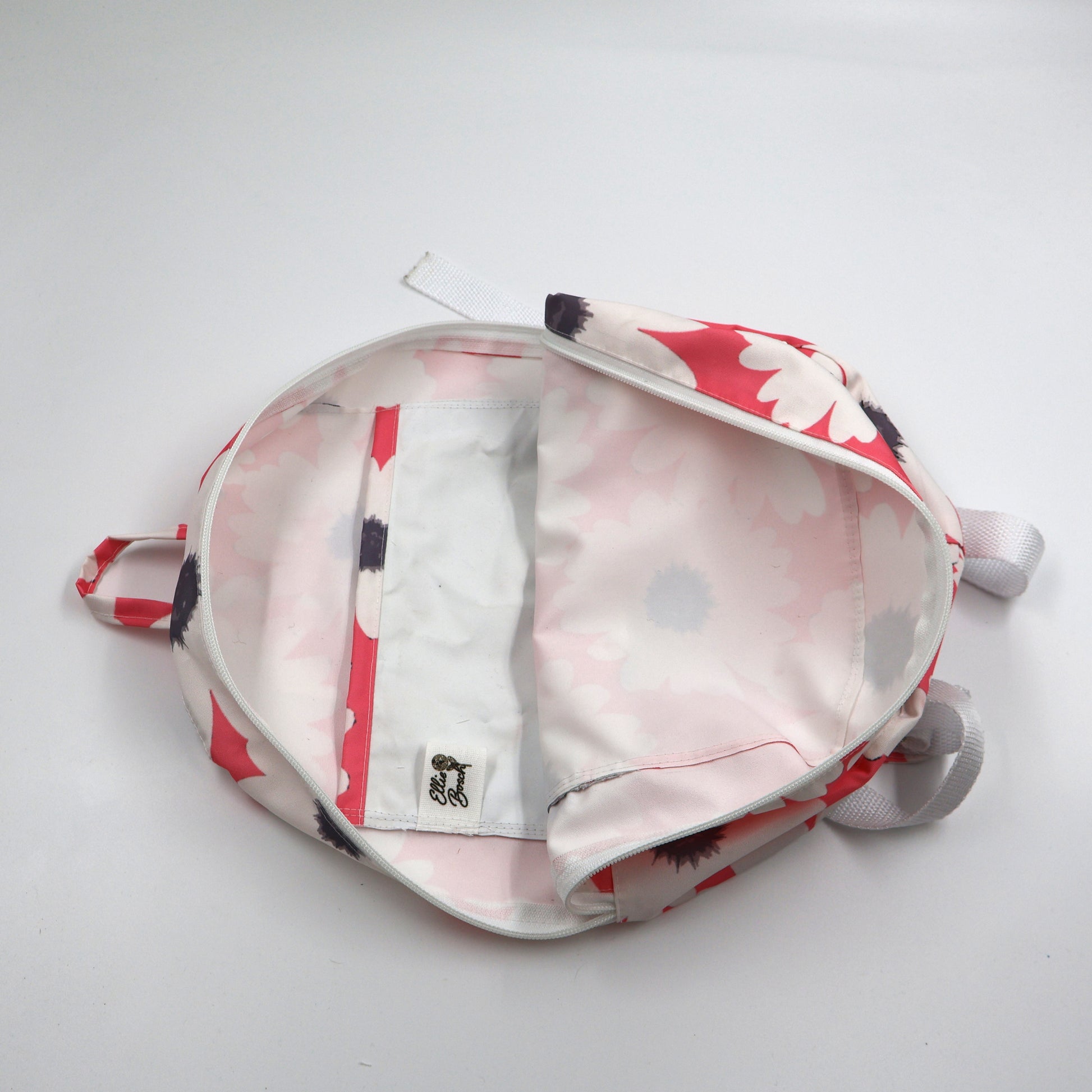 Flat-lay view of an open small pink backpack revealing the protective cotton twill inner lining and interior storage pocket finishes.