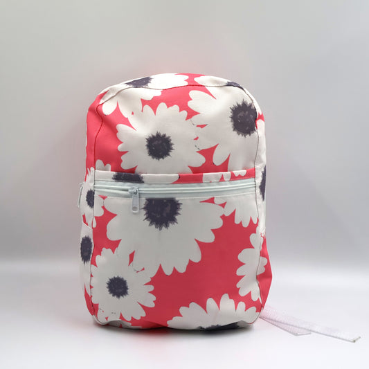 Front view of a small pink water-resistant polyester canvas backpack highlighting the secure zippered front pocket.