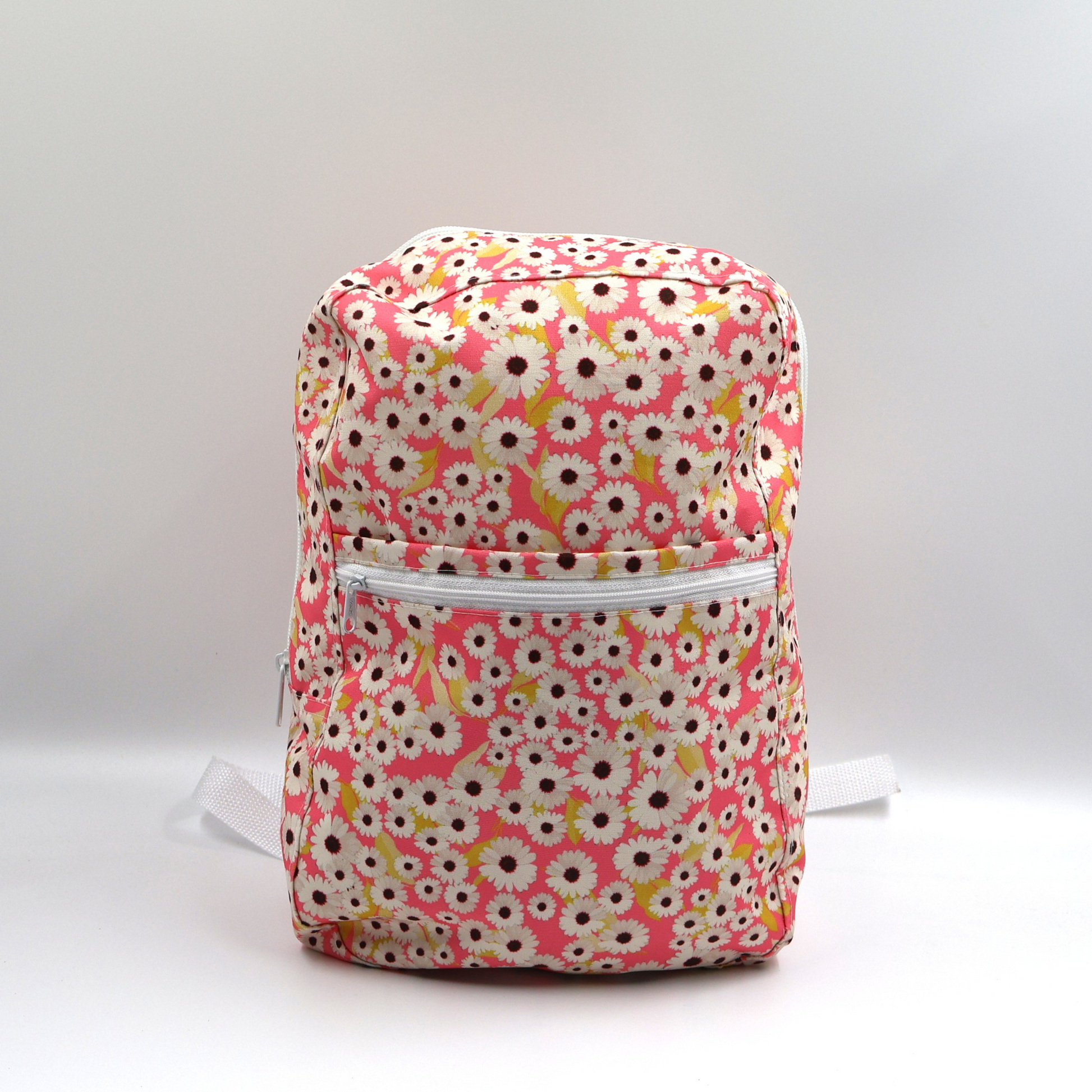 Front view of a small pink water-resistant polyester canvas backpack highlighting the secure zippered front pocket