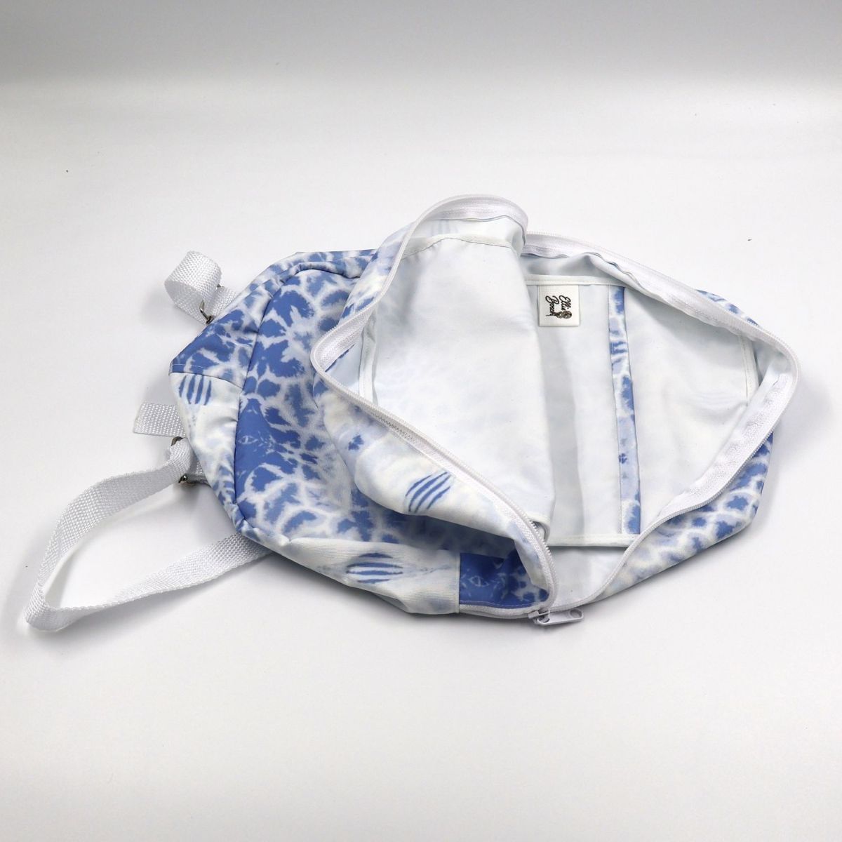 Flat-lay view of an open small blue giraffe backpack revealing the protective cotton twill inner lining and interior storage pocket finishes
