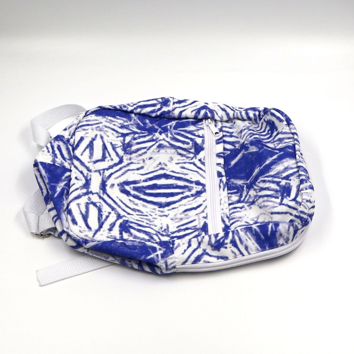 A small zippered pouch with a blue and white tie-dye pattern, featuring a front zipper pocket and white webbing straps, photographed on a white background.